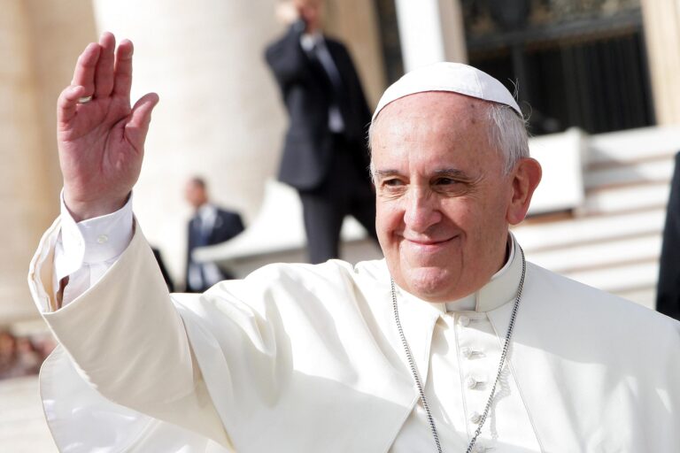 Pope Francis smiles slightly and waves